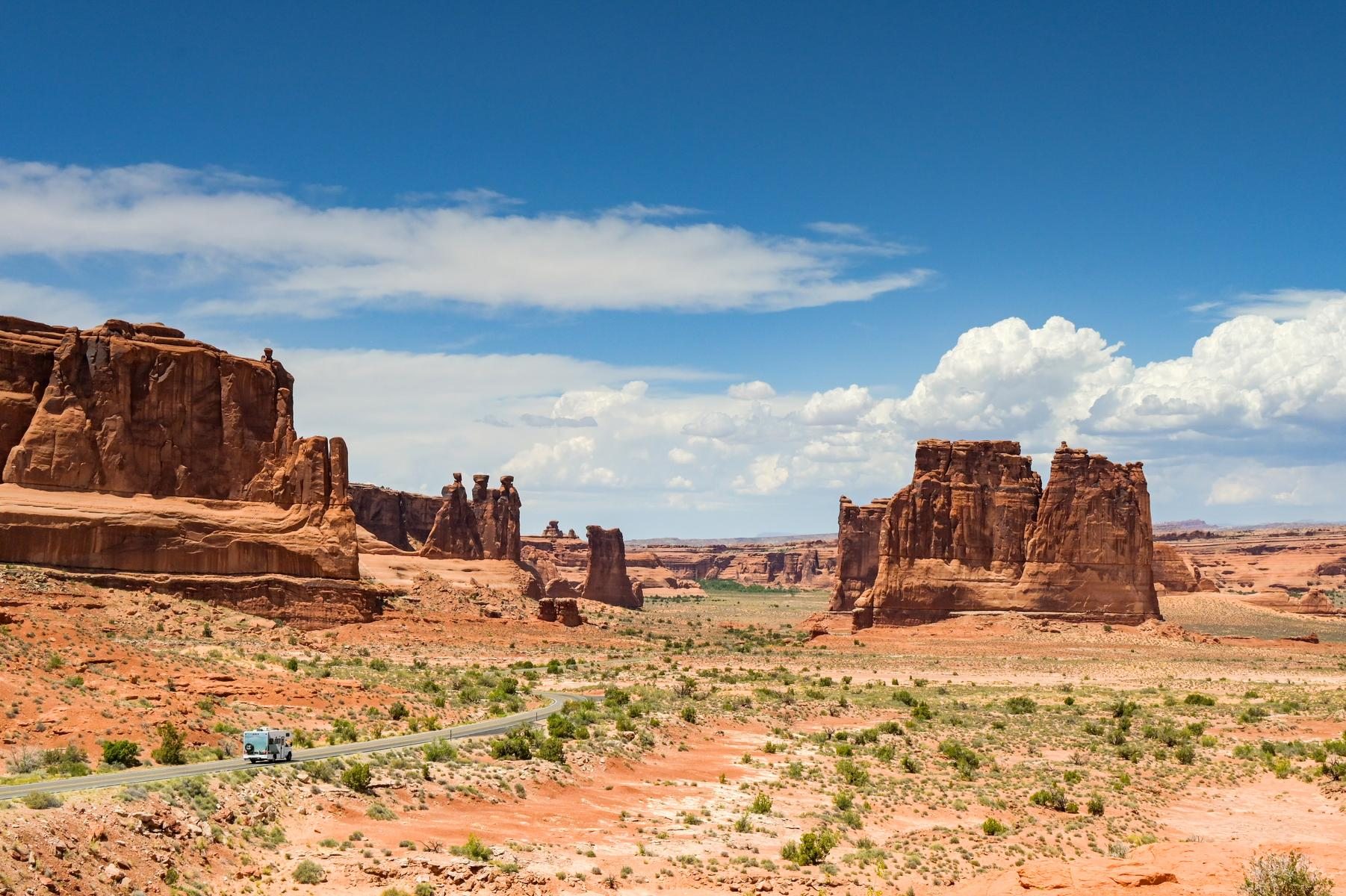 Wide desert valley with red sandstone buttes and a road crossing it
