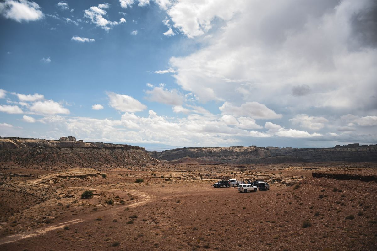 Two vehicles at a dispersed camping area on open desert land below red cliffs, San Rafael Swell, Utah