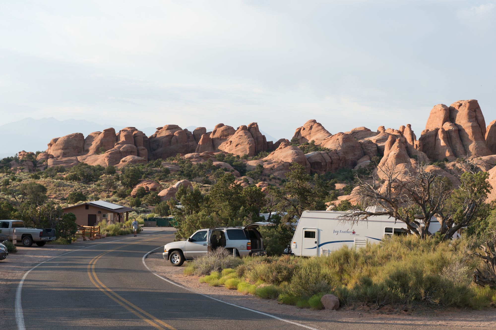 Campsites with an SUV and a travel trailer below red sandstone fins at Devils Garden Campground, Arches National Park