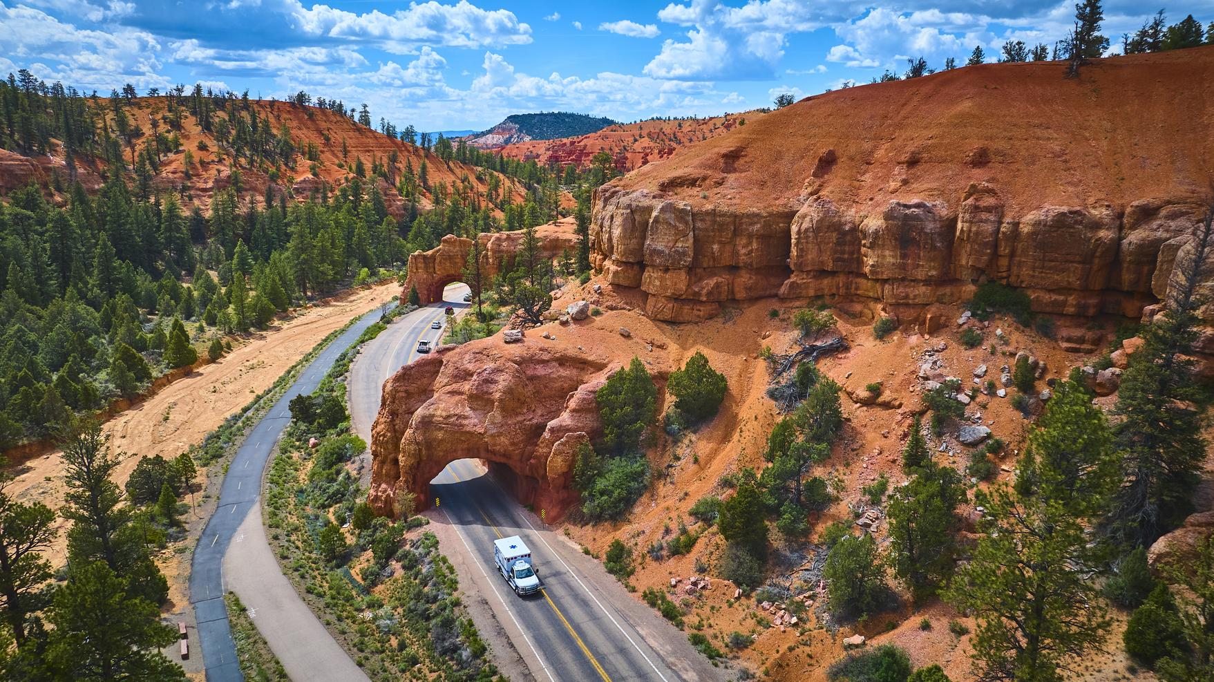 Highway through two red-rock arch tunnels in Red Canyon, Utah, seen from above
