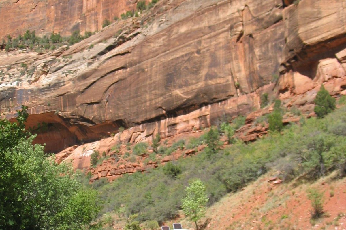 A Zion Canyon shuttle bus on the Scenic Drive below towering red sandstone walls