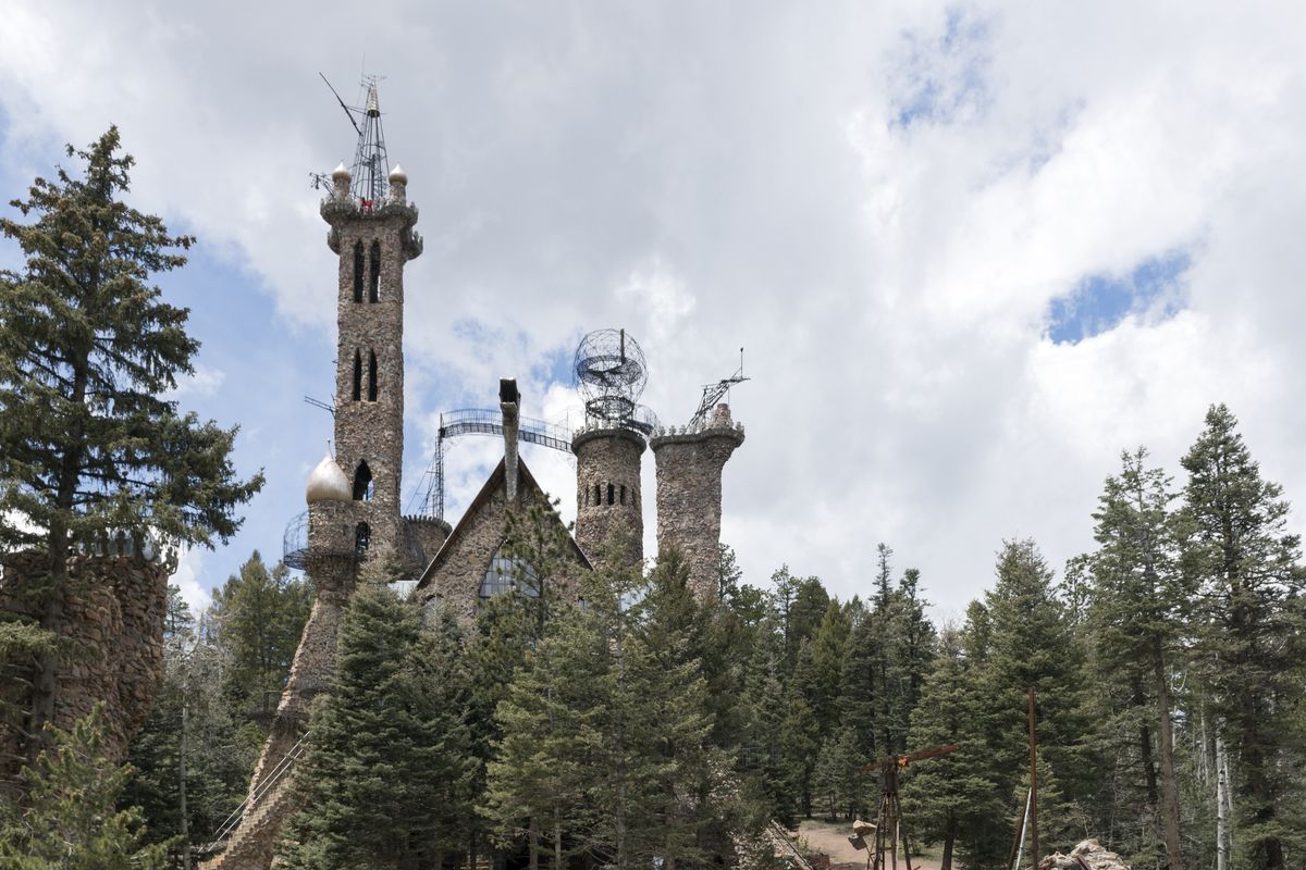 Bishop Castle in the Colorado forest: tall stone towers with metal spires and a steep roof, rising above pine trees