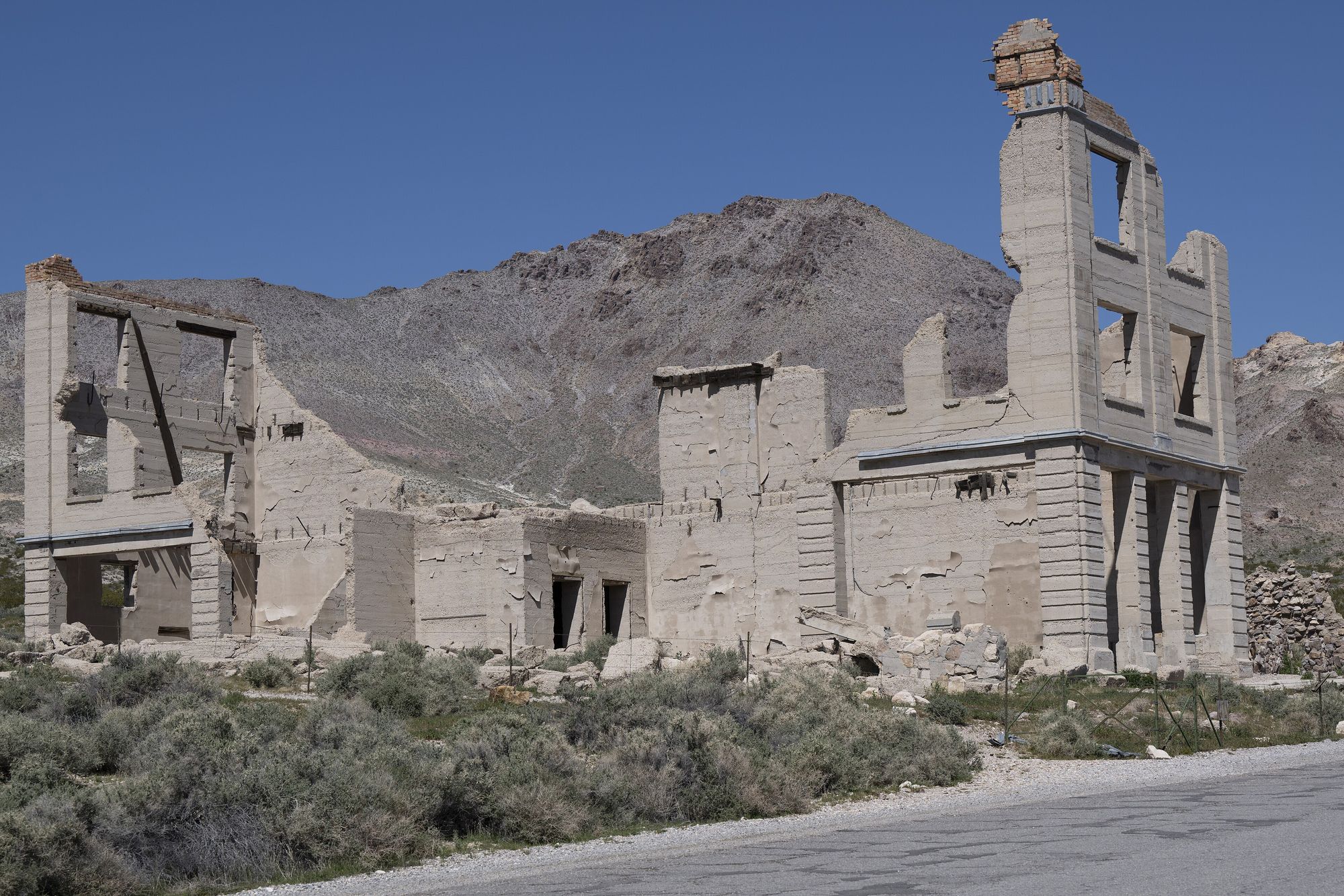 The roofless three-storey ruin of the Cook Bank building in the Rhyolite ghost town, desert hills and blue sky behind