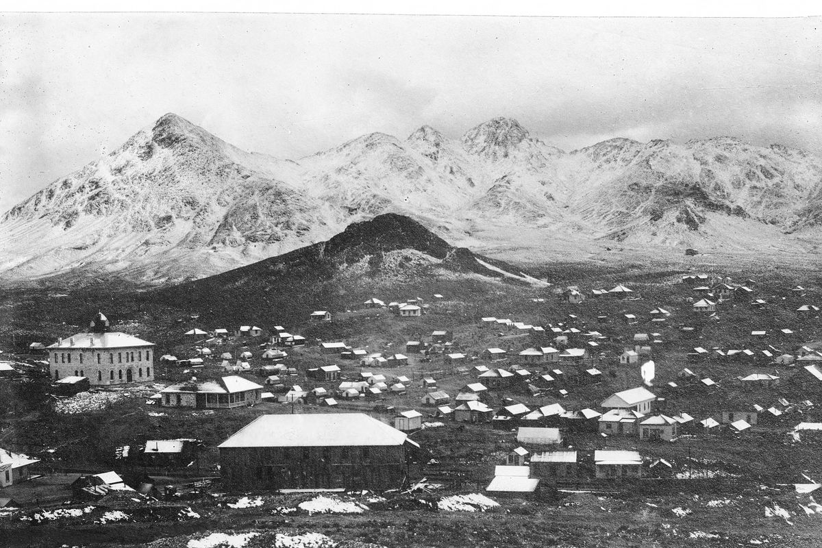 Black-and-white panorama of the Tonopah mining camp around 1904, wooden buildings and mine works below snow-covered Mount Butler